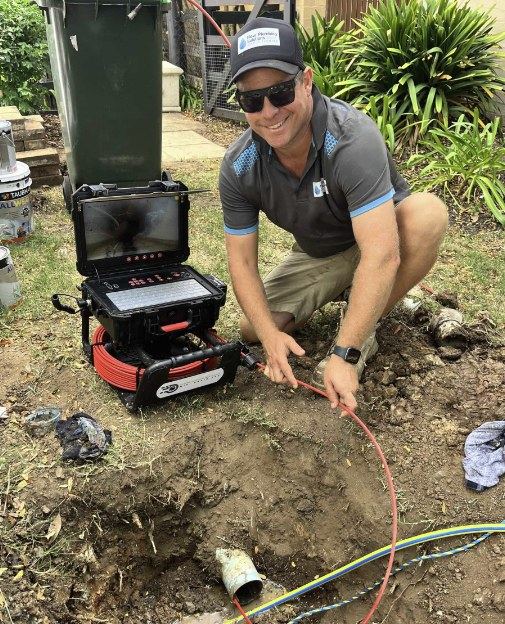 Flow Plumbing Solutions plumber feeding a drain camera into a pipe